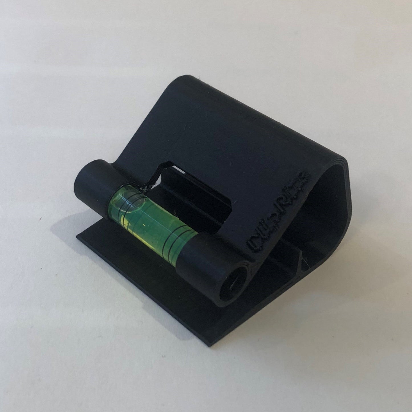 Black hands-free plastic clip-on level, designed for easy attachment to surfaces, featuring a built-in bubble vial for precise alignment during leveling tasks
