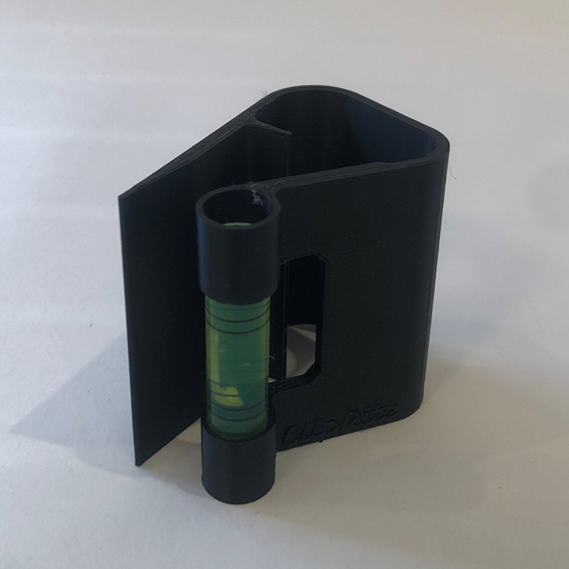 Black hands-free plastic clip-on level, designed for easy attachment to surfaces, featuring a built-in bubble vial for precise alignment during leveling tasks