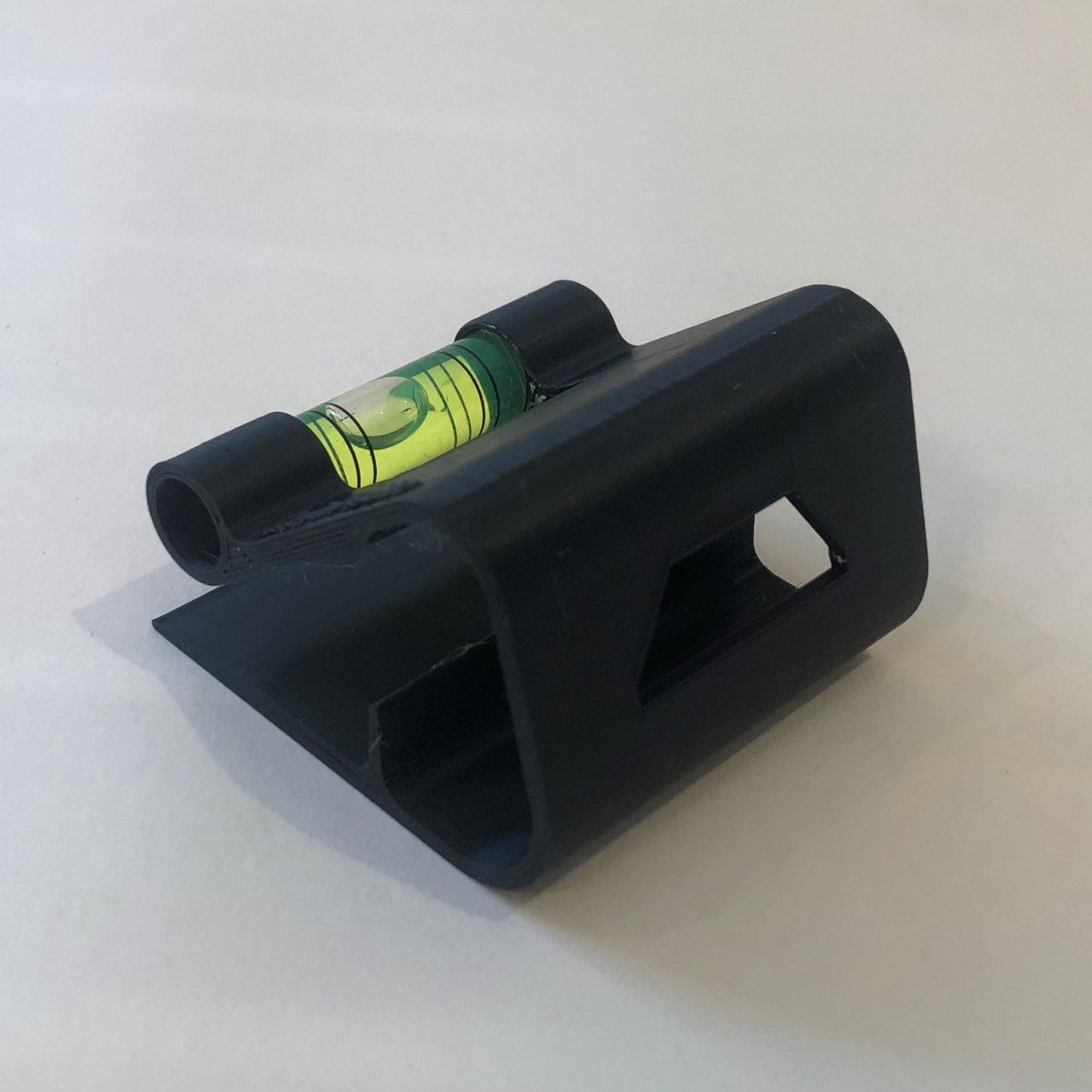 Black hands-free plastic clip-on level, designed for easy attachment to surfaces, featuring a built-in bubble vial for precise alignment during leveling tasks