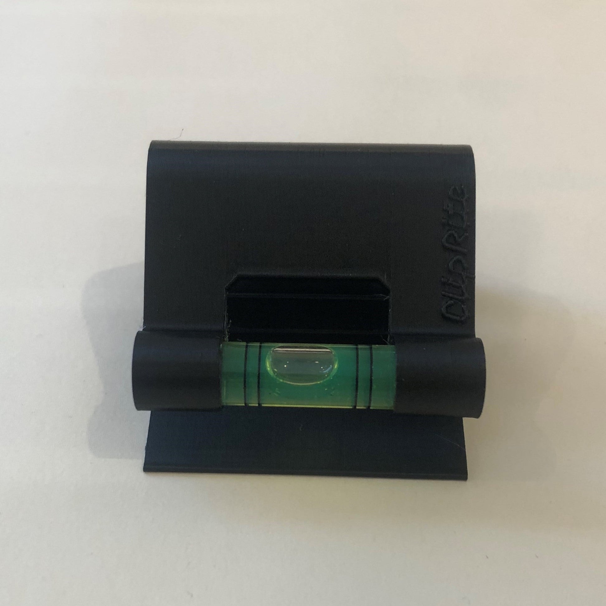 Black hands-free plastic clip-on level, designed for easy attachment to surfaces, featuring a built-in bubble vial for precise alignment during leveling tasks