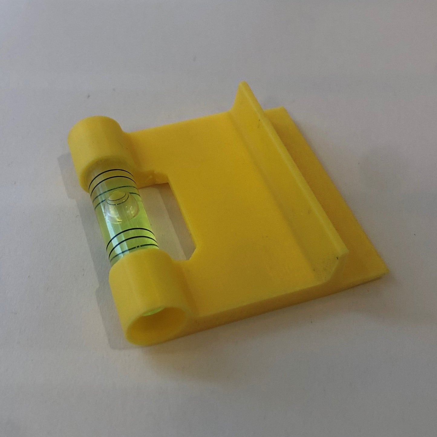 Yellow hands-free plastic clip-on level, designed for easy attachment to surfaces, featuring a built-in bubble vial for precise alignment during leveling tasks for floating picture frames