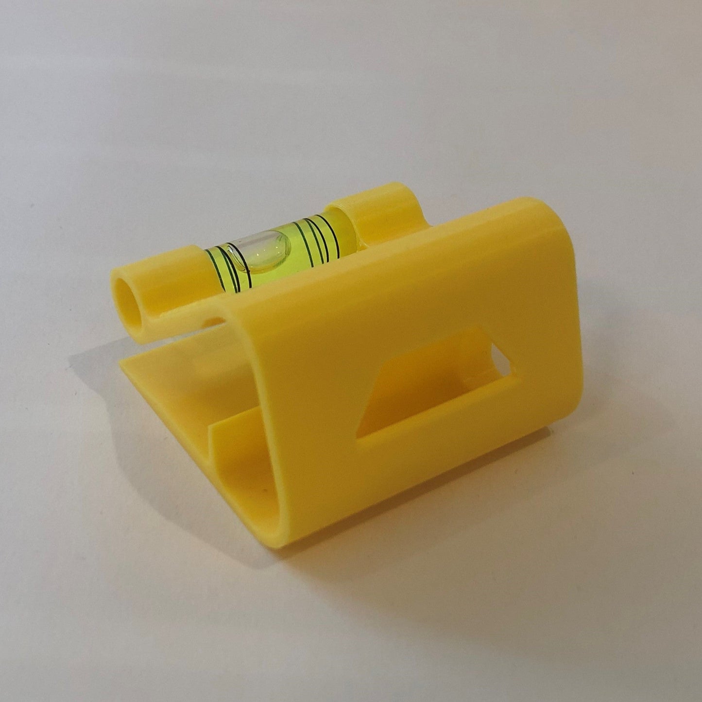 Yellow hands-free plastic clip-on level, designed for easy attachment to surfaces, featuring a built-in bubble vial for precise alignment during leveling tasks