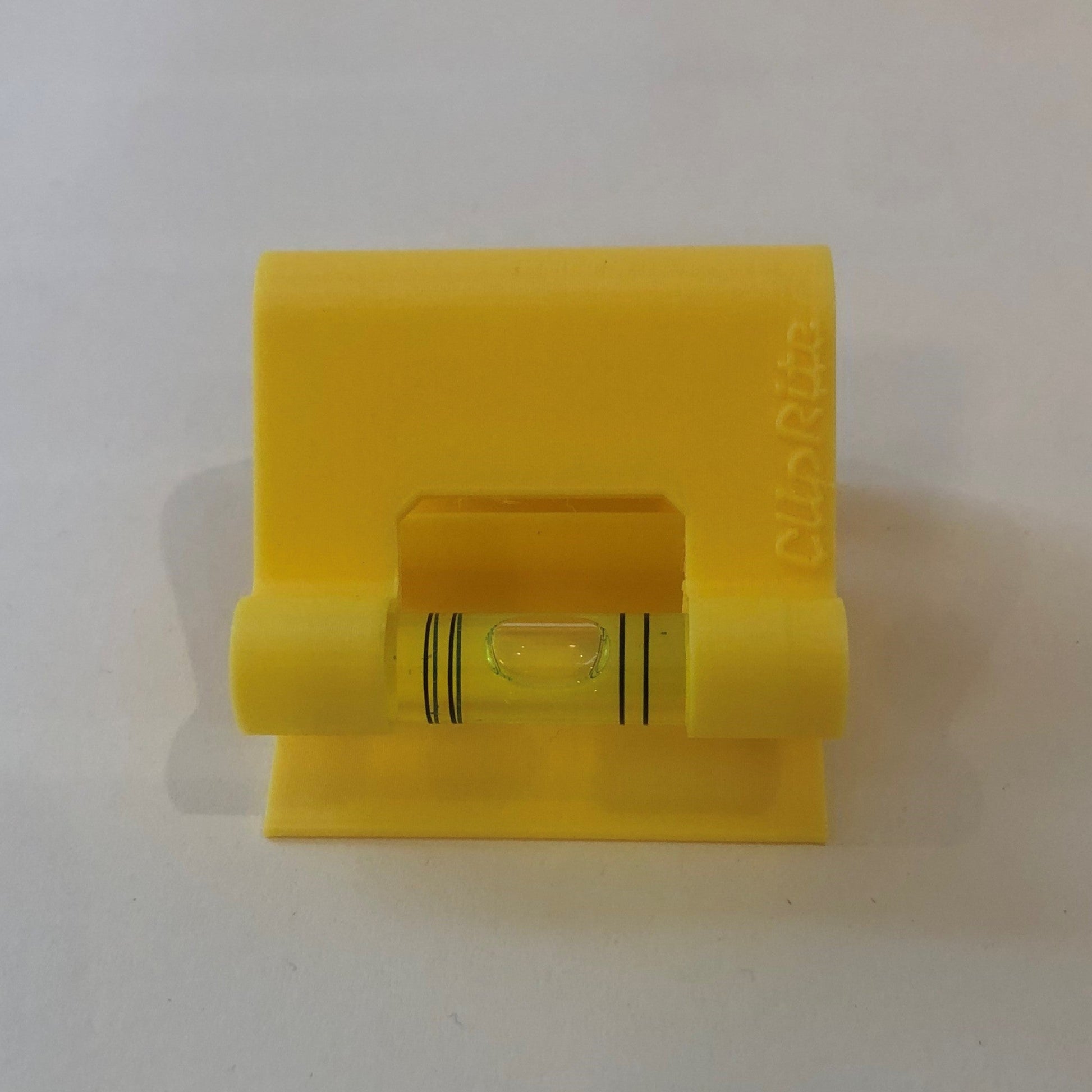Yellow hands-free plastic clip-on level, designed for easy attachment to surfaces, featuring a built-in bubble vial for precise alignment during leveling tasks